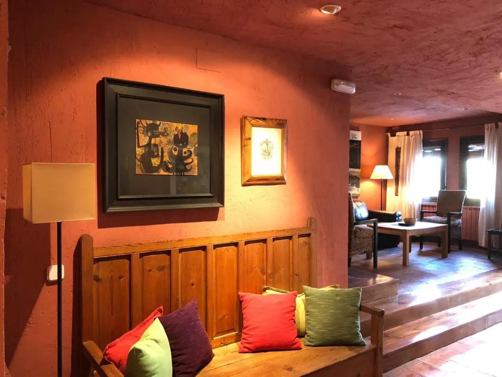 Salón de La Casa de San Pedro con paredes rojizas y obras enmarcadas