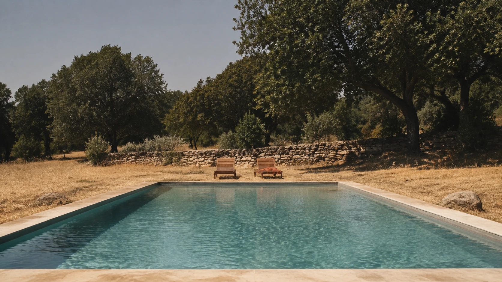 Casas rurales con piscina en Cuenca: piscina rectangular al borde de un prado seco y tumbonas vacías