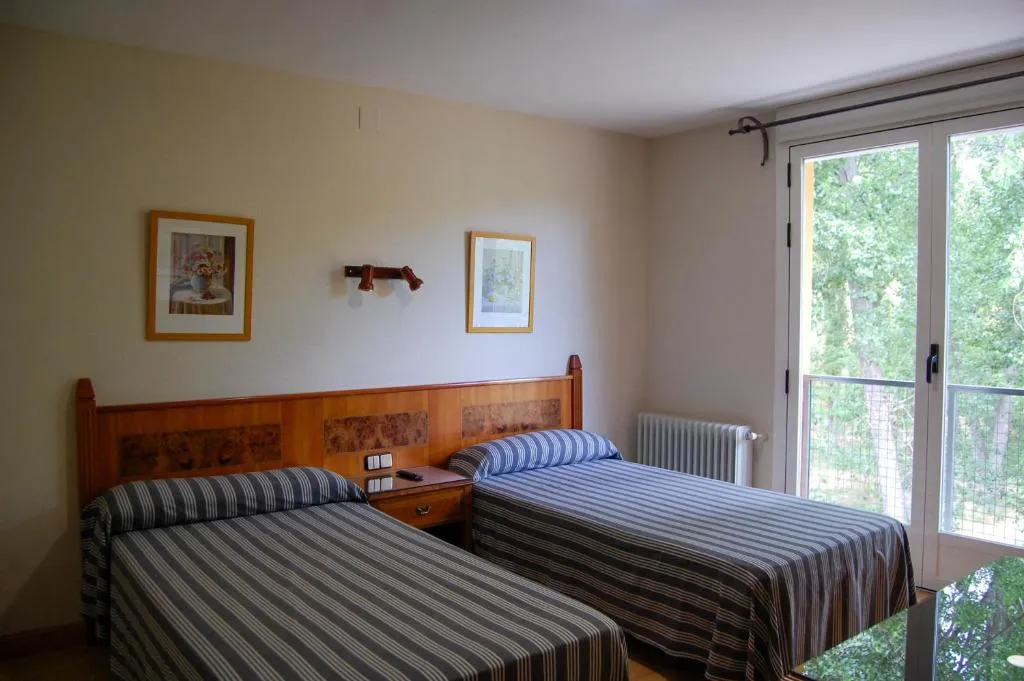 Dormitorio del Hotel El Tablazo con dos camas y puerta acristalada al jardín