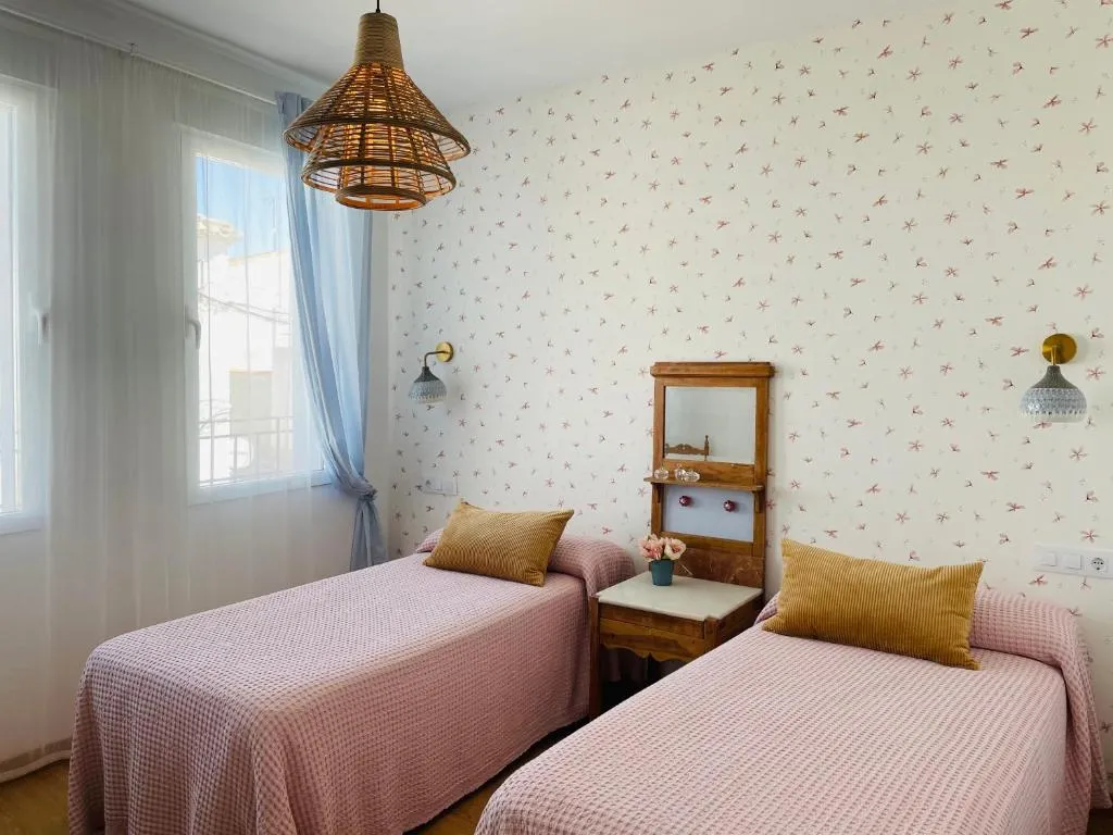 Dormitorio de El Paseo en Belmonte con dos camas y pared clara