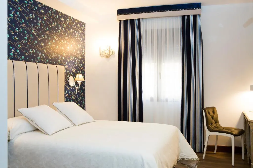 Dormitorio del Hotel Hierbaluisa en Alarcón con dos camas y pared decorada