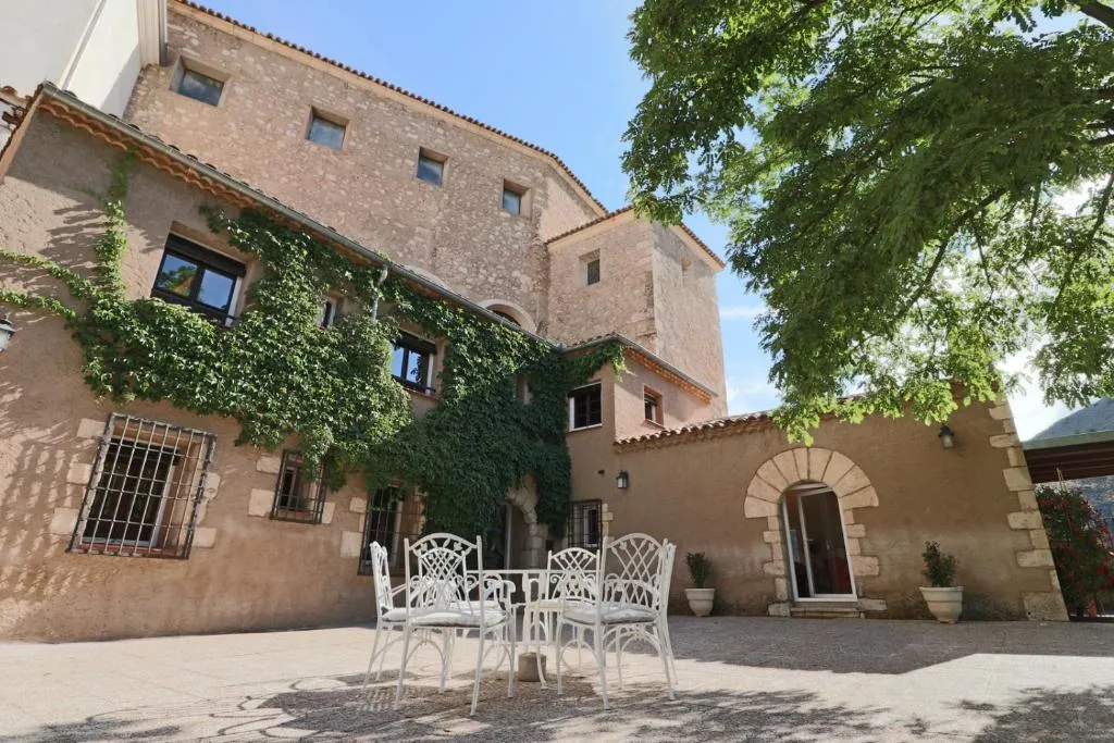 Patio de piedra de Huerto de Mateo Arana con la casa y árboles al fondo