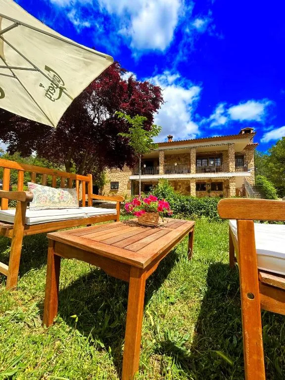 Zona ajardinada de Villa Sanz con mesa exterior y árboles