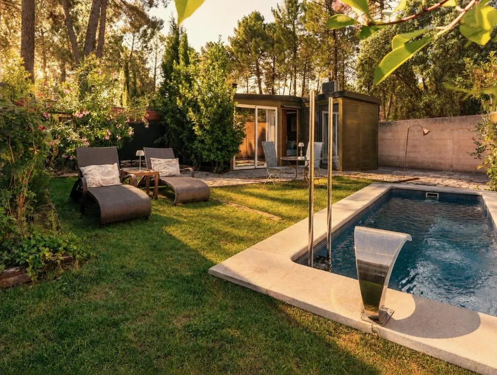 Jardín del Hotel Boutique Pinar entre pinos, con piscina y cabaña de madera