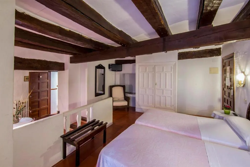 Habitación abuhardillada de la Posada San José con vigas de madera y cama doble