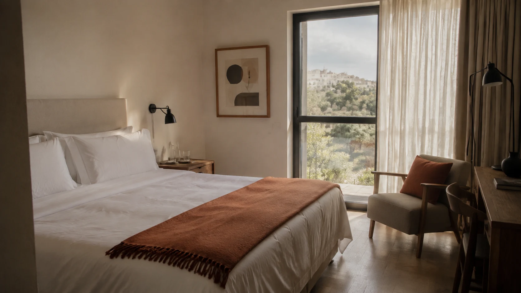 Hoteles en Cuenca: cama hecha y lámpara de lectura en una habitación de paredes claras