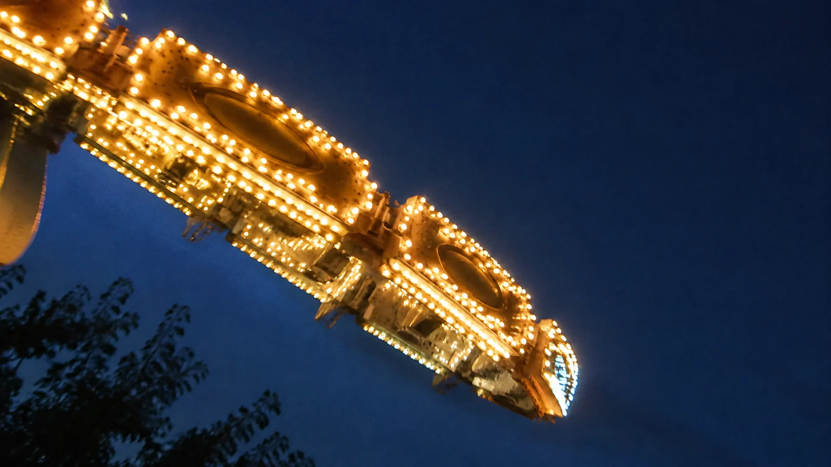 Luces de atracciones de feria encendidas al anochecer en Cuenca