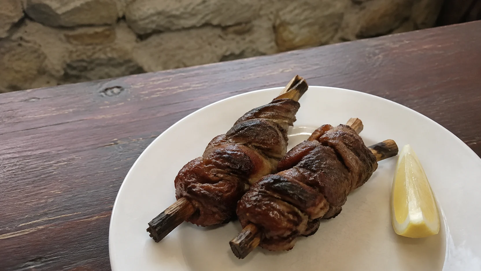 Zarajos enrollados en sarmiento sobre un plato blanco