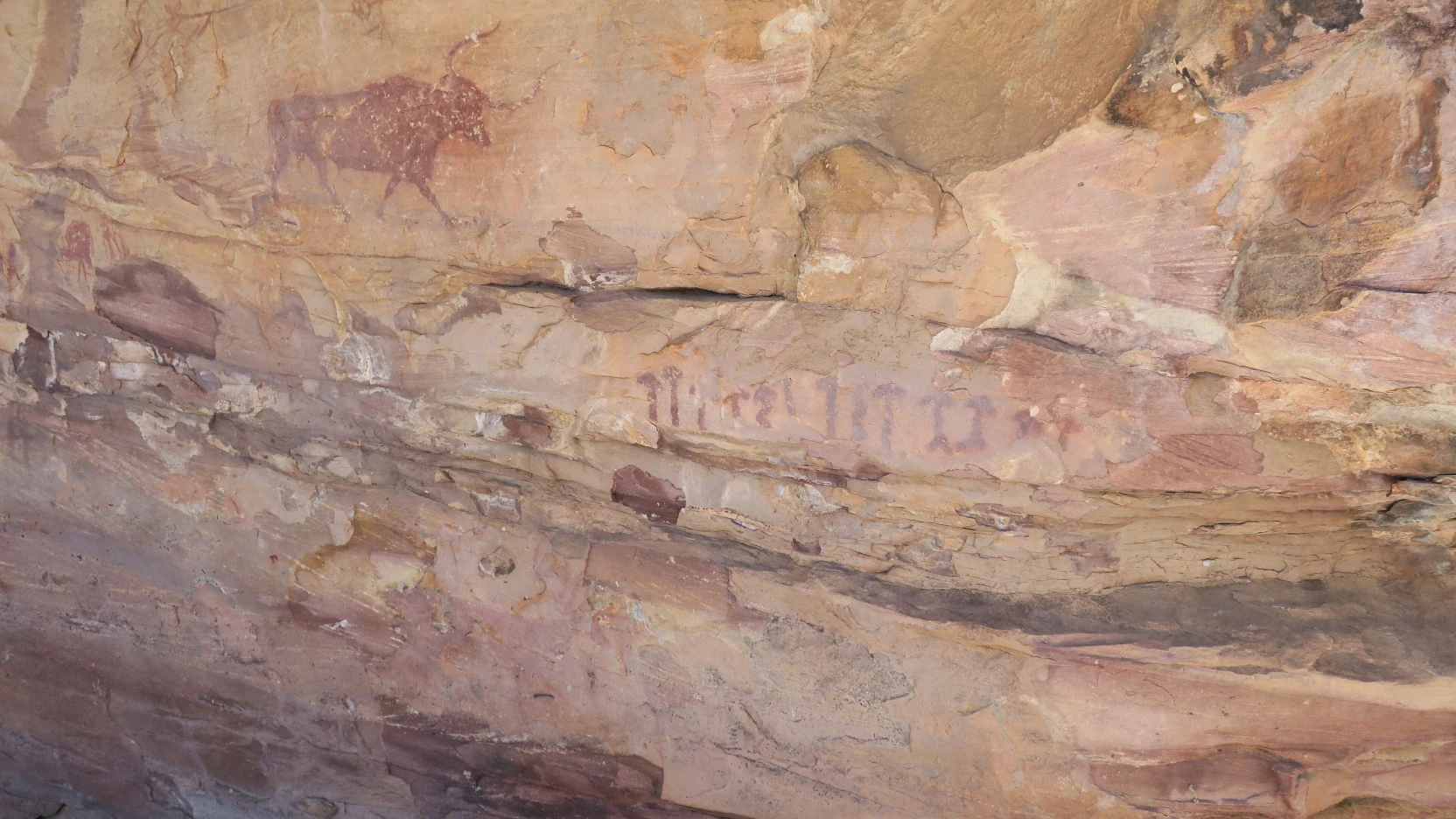 Abrigo rocoso con pinturas apenas visibles en una ladera de monte bajo