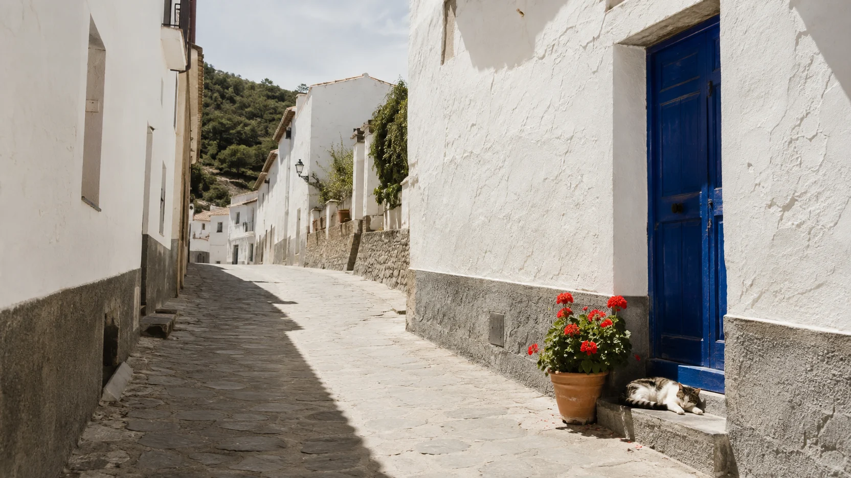 Pueblos de Cuenca: calle encalada con zócalo de piedra y una puerta de madera azul