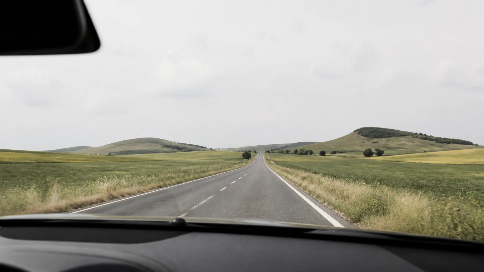 Cómo llegar a Cuenca: carretera de dos carriles entre campos abiertos vista desde el copiloto