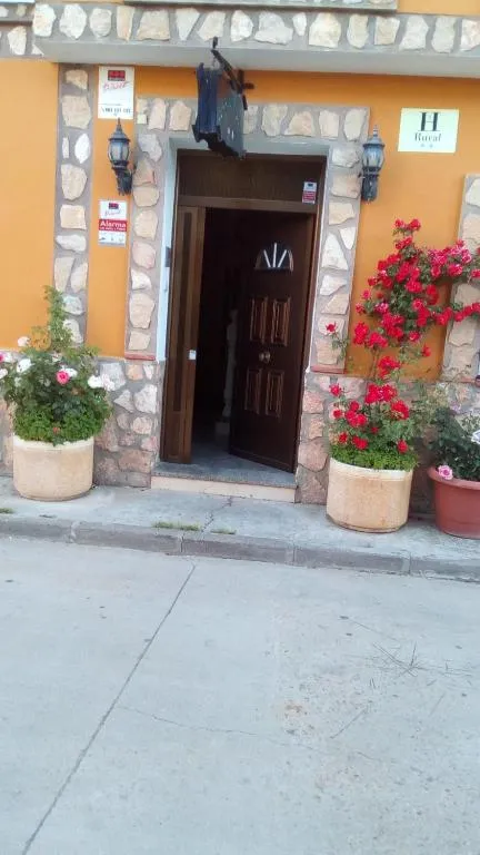 Entrada del Hostal Cañamares en una calle de Cañamares, con flores junto a la puerta