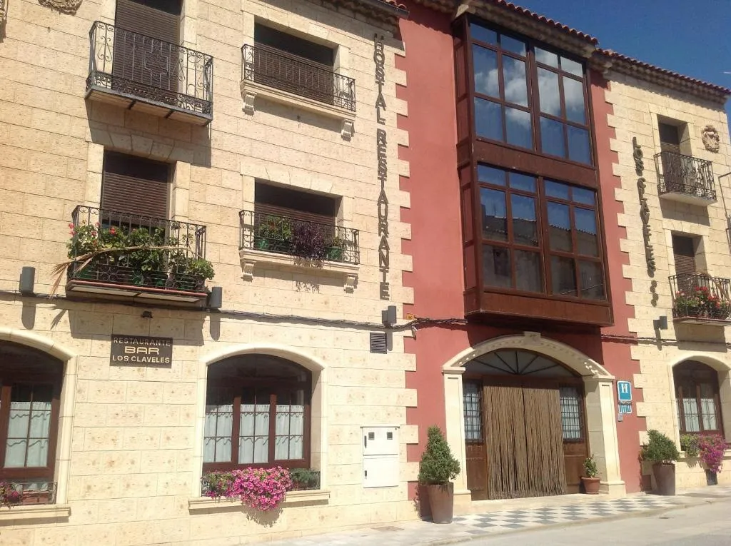 Fachada de piedra del Hostal Los Claveles en una calle de Priego