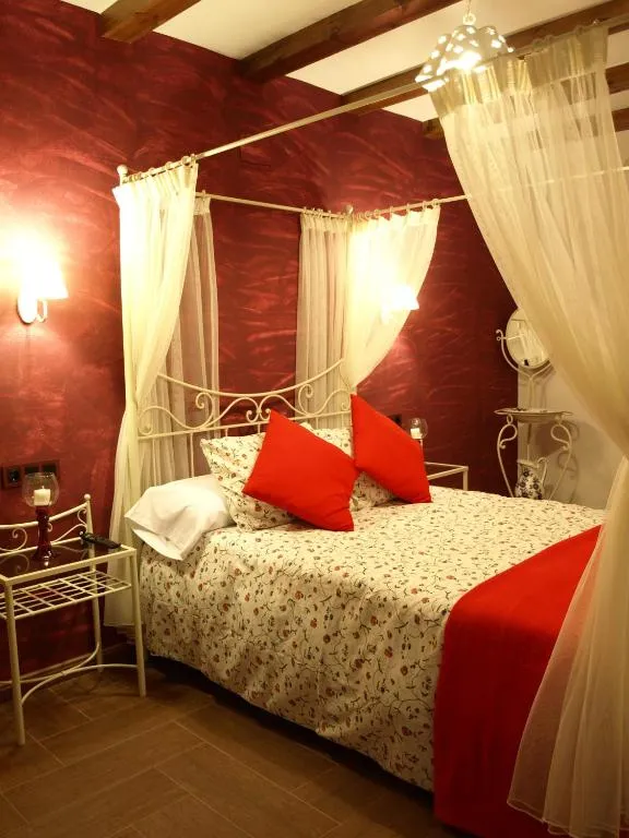 Dormitorio de Apartamentos Rurales El Palomar con cama con dosel y paredes rojas