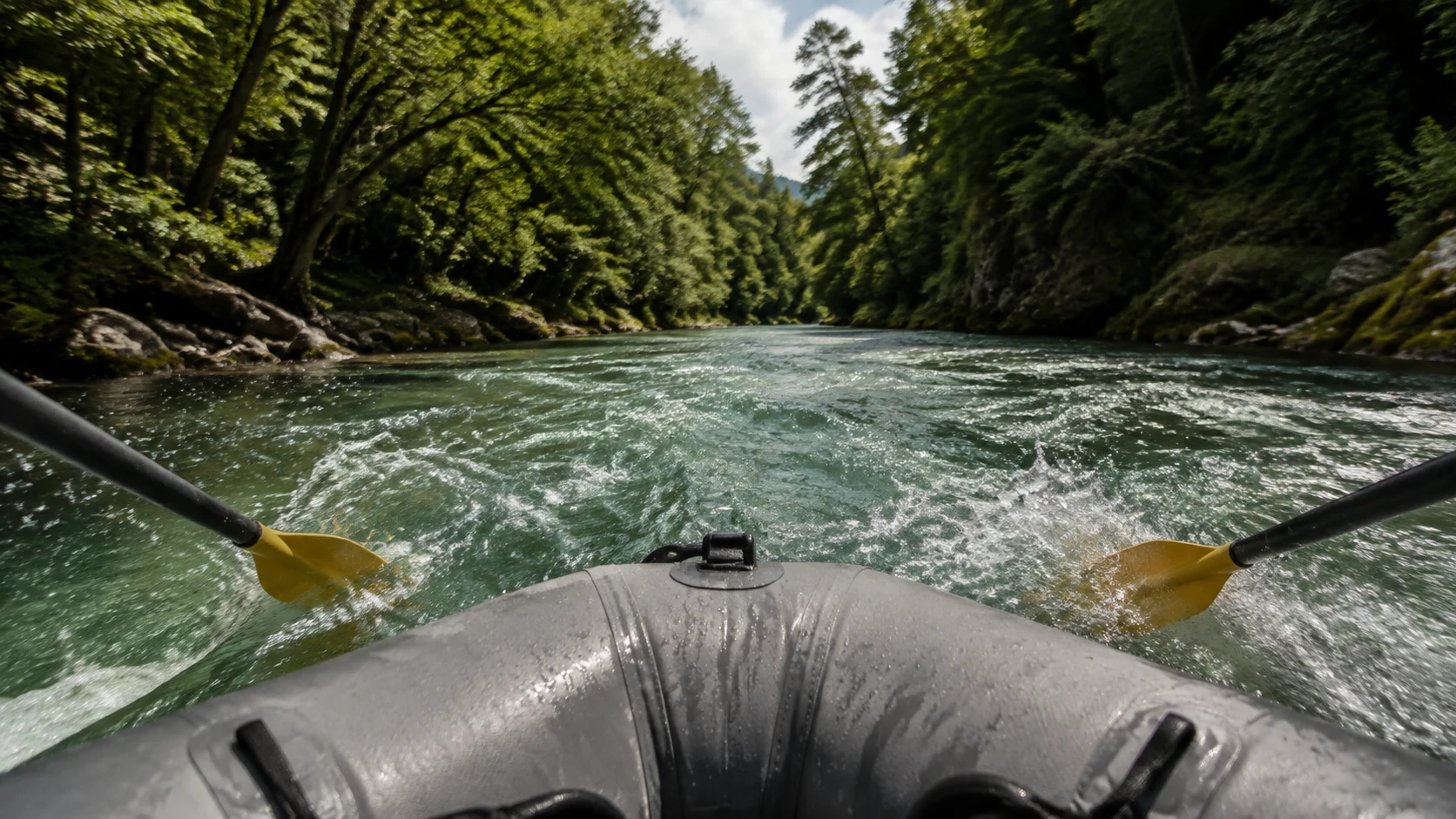 Rafting en Cuenca: proa de una balsa hinchable y palas entrando en agua verde